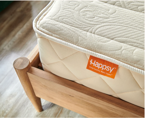 Beige mattress on a wooden bed frame with a Happsy logo.