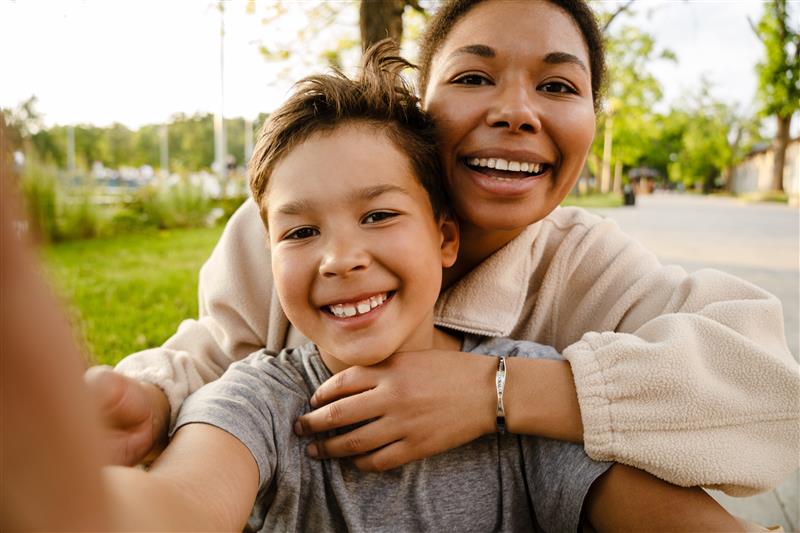 Woman and child hugging outdoors with a blurred background
