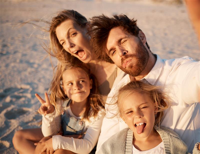 Family of four making silly faces on a sandy beach
