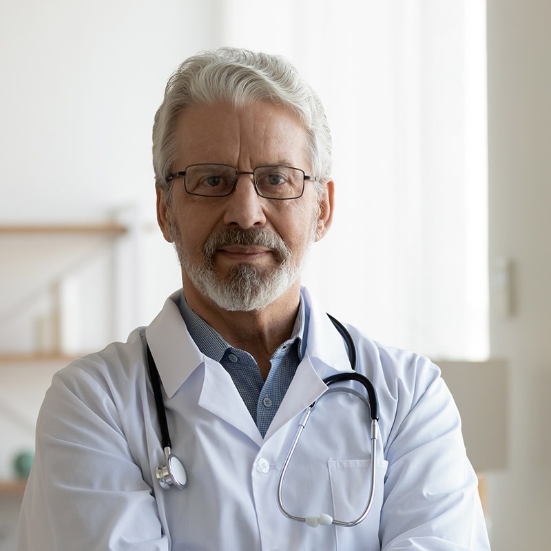 Elderly male doctor in white medical uniform.